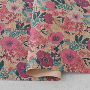 Puede incluir: Una lámina de tela de corcho con un estampado floral de flores rosas, magenta y blancas, acentuado por hojas y tallos de color verde azulado y verde oscuro. La textura natural del corcho tostado sirve de fondo para el diseño botánico.