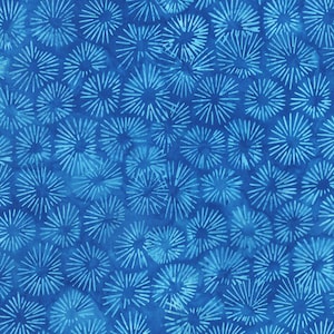 Op de afbeelding: Een blauwe stof met een wit patroon van gestileerde zonnestralen of sterren. De stof heeft een textuur, een licht ruw oppervlak.