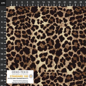 May include: A close-up of a fabric with a leopard print pattern. The design features dark brown spots on a tan and light brown background. The fabric has the Oeko-Tex Standard 100 label.