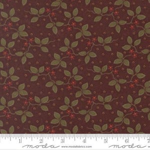 May include: A dark maroon fabric featuring a repeating pattern of olive green leaves, small red flowers, and tiny tan dots. A white ruler is visible at the bottom edge, showing measurements in inches from 1 to 7, with the text moda fabrics.