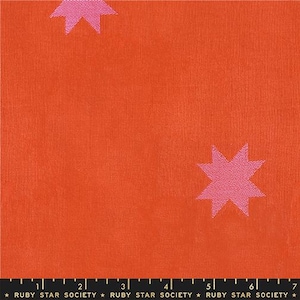 May include: Close-up of orange fabric with a repeating pattern of pink stars. The fabric has a textured appearance. The bottom of the image has a ruler with the text "RUBY STAR SOCIETY".