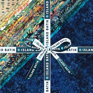 Könnte beinhalten: Ein Stapel quadratischer Stoffzuschnitte mit verschiedenen Batikmustern in Blau-, Grün-, Orange- und Beigetönen. Das Stoffbündel ist mit einem weißen Band zusammengebunden, das mit dem blauen Text ISLAND BATIK bedruckt ist und eine Schleife bildet.