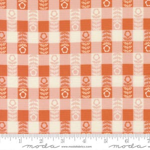 Op de afbeelding: Close-up van een stof met een herhalend patroon van oranje en crèmekleurige ruitjes. Verticale kolommen bloemstengels met oranje bloemen en bladeren wisselen af met de ruitjes. De stof heeft een liniaal aan de onderkant.