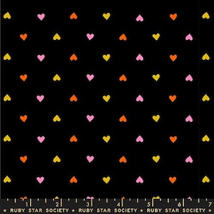 Op de afbeelding: Zwarte stof met een herhalend patroon van kleine gele, oranje en roze hartjes. De hartjes zijn gelijkmatig verdeeld. De tekst "RUBY STAR SOCIETY" staat onderaan.