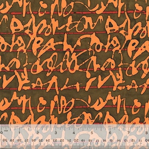 Puede incluir: Tela con un diseño abstracto de formas anaranjadas similares a escritura sobre un fondo verde oliva oscuro. Finas líneas horizontales rojas cruzan el diseño. Una regla en la parte inferior muestra medidas en centímetros.