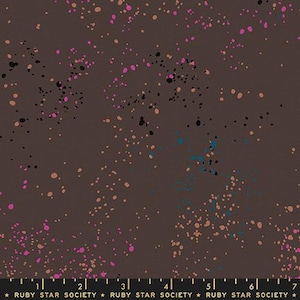 Puede incluir: Tela marrón con un patrón moteado. El diseño presenta puntos irregulares en tonos de rosa, negro, turquesa y beige, dispersos por la superficie. El borde inferior incluye el texto "RUBY STAR SOCIETY".