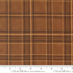Peut inclure: Un tissu marron avec un motif à carreaux composé de lignes marron foncé et de fines lignes jaune doré. Le tissu est placé au-dessus d'une règle blanche graduée en pouces, avec le texte moda www.modafabrics.com imprimé en dessous.