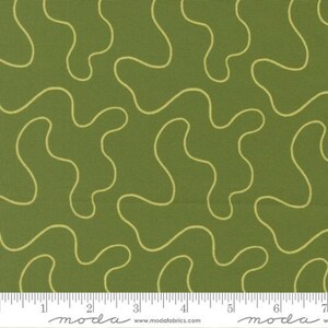 May include: Close-up of a green fabric with a repeating pattern of wavy, light yellow lines. The fabric has a textured appearance. A ruler is at the bottom of the image, with the word "moda" printed on it.