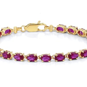 Peut inclure: Un bracelet en or avec une rangée de pierres précieuses rubis ovales.