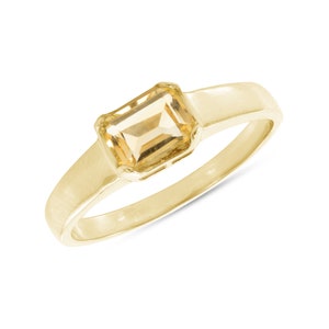 May include: A gold ring with a light brown, emerald-cut gemstone.