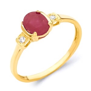 May include: A gold ring with a red oval gemstone and two smaller clear gemstones on the band.