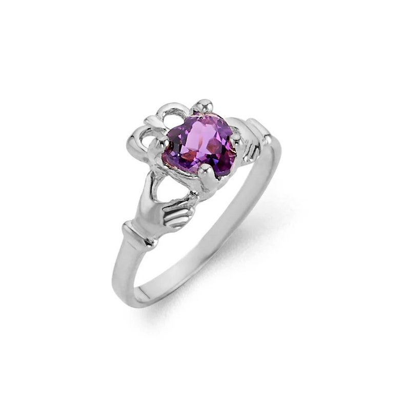 May include: A silver ring with a purple heart-shaped gemstone. The ring features a Celtic knot design with two hands clasped together.
