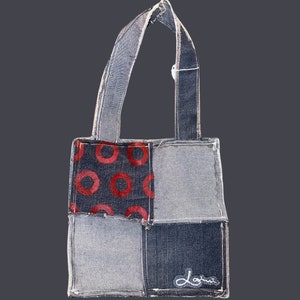 May include: A denim tote bag with a patchwork design. The bag has a red and blue pattern with circles on one side and the word "denim" on the bottom.