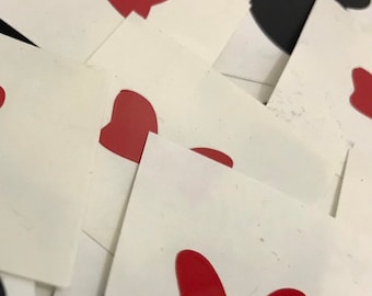 Może przedstawiać: Stos białych naklejek papierowych z czerwonymi wzorami kokardek.