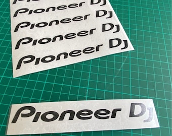 Może przedstawiać: Kilka białych naklejek z nadrukiem "Pioneer DJ" w kolorze czarnym. Naklejki są ułożone w stos, a górna naklejka częściowo zakrywa naklejkę znajdującą się pod nią.