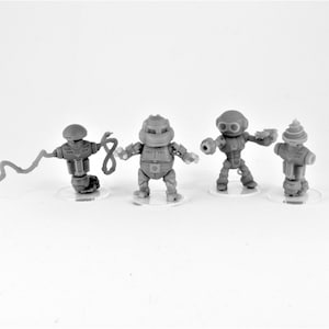 May include: Four gray robot figurines with different designs and poses. The robots are standing on clear plastic bases.