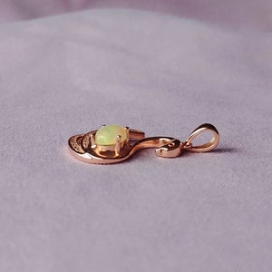 May include: A rose gold pendant with a light green opal gemstone set in a swirl design.