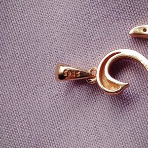 May include: A gold pendant necklace with a detailed design featuring a heart shape and a small pearl. The pendant is marked with the number "5925".