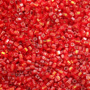 May include: A close-up image of a large quantity of small, red, glass beads. The beads are square shaped and have a shiny, translucent finish.
