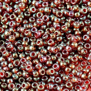May include: A close-up image of a large quantity of small, round, red and green iridescent glass beads. The beads are arranged in a random pattern and are all the same size.