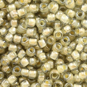 May include: A close-up of a pile of small, round, translucent beads. The beads are a light beige color with a subtle shimmer. They are arranged in a random pattern.