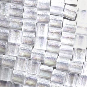 May include: A close-up of a silver iridescent mosaic tile sheet. The tiles are small and rectangular, arranged in a staggered pattern.
