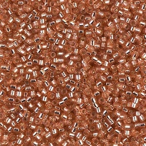 May include: A close-up image of a large quantity of small, round, copper-colored beads. The beads have a metallic sheen and are arranged in a random pattern.