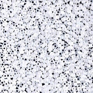 May include: A close-up image of a large quantity of small, clear glass beads. The beads are round and have a hole in the center. They are arranged in a random pattern.