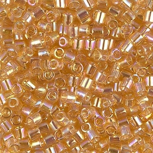 May include: A close-up image of a large quantity of small, round, gold-colored glass beads. The beads have a slightly iridescent finish, giving them a subtle shimmer.
