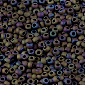 May include: A close-up view of a pile of small, round, iridescent beads. The beads are a dark brown color with a hint of purple and green.