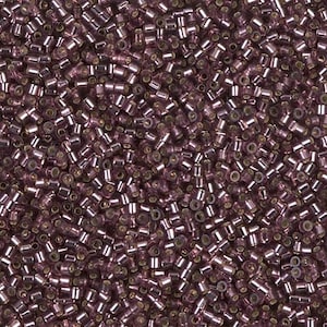 May include: A close-up view of a large quantity of small, round, purple glass beads. The beads have a metallic sheen and are arranged in a random pattern.