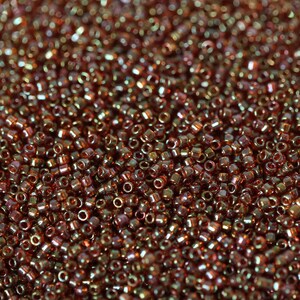 May include: A close-up image of a large quantity of small, round, iridescent brown seed beads.