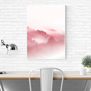 May include: A digital art print of a foggy forest scene in shades of pink and white. The print is framed and hanging on a white brick wall above a desk with a lamp and a plant.