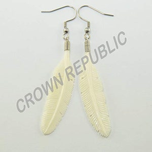 May include: A pair of white feather earrings with silver hooks. The feathers are carved with detailed lines and have a smooth, polished finish.