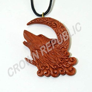May include: A wooden pendant necklace featuring a carved wolf howling at the moon. The pendant is made of reddish-brown wood and has intricate details.