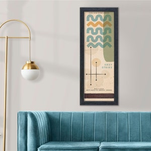 May include: A vintage-style poster with a geometric design in shades of blue, yellow, and brown. The poster features a stylized image of waves and a circle with the text "Easy Strike" inside. The poster is framed in black and has a white background.