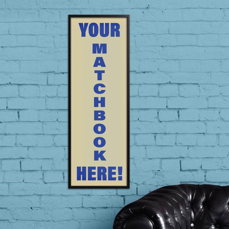 May include: A framed sign with a white background and black frame. The sign says "YOUR MATCHBOOK HERE!" in blue letters.