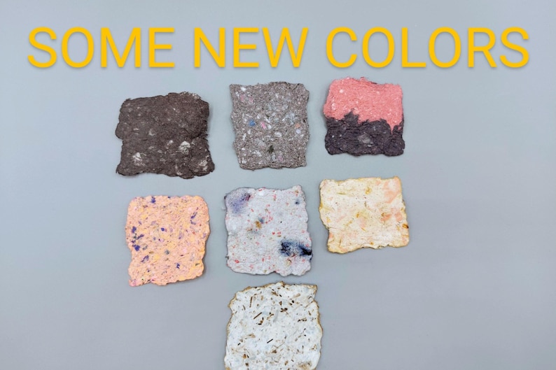 May include: The image displays six textured, square-shaped paper samples in various colors, including brown, gray, pink, peach, white, and a speckled mix. The text "SOME NEW COLORS" is in yellow above the samples.
