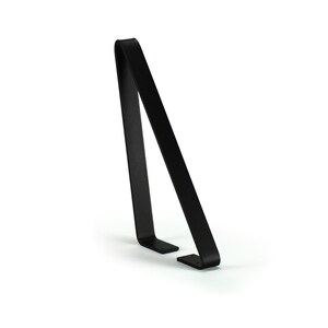 May include: A minimalist black metal stand with a curved top and two small feet. The stand has a sleek, modern design and is suitable for displaying various items. The stand is made of a solid, durable material.