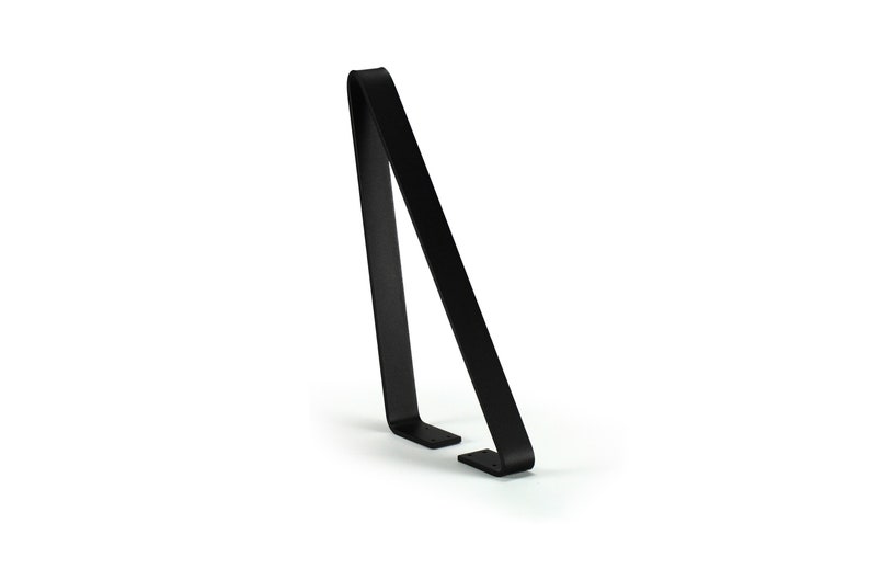 May include: A minimalist black metal stand with a curved top and two small feet. The stand has a sleek, modern design and is suitable for displaying various items. The stand is made of a solid, durable material.