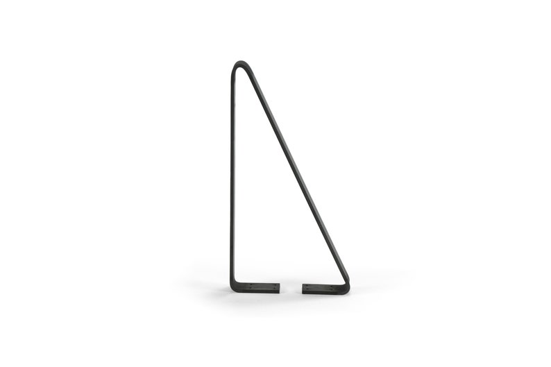 Puede incluir: Un atril minimalista de metal negro. El soporte tiene forma triangular con una parte superior curvada y dos pies planos. El dise&ntilde;o es sencillo y moderno, adecuado para exhibir libros u obras de arte.