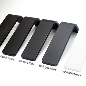May include: A collection of angled, L-shaped display stands in various colors. The colors include shadow black, jet black texture, silk matte black, black-grey texture, and signal white texture. Each stand has a flat top and a bent, angled support.
