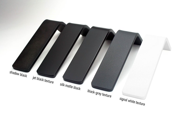 May include: A collection of angled, L-shaped display stands in various colors. The colors include shadow black, jet black texture, silk matte black, black-grey texture, and signal white texture. Each stand has a flat top and a bent, angled support.