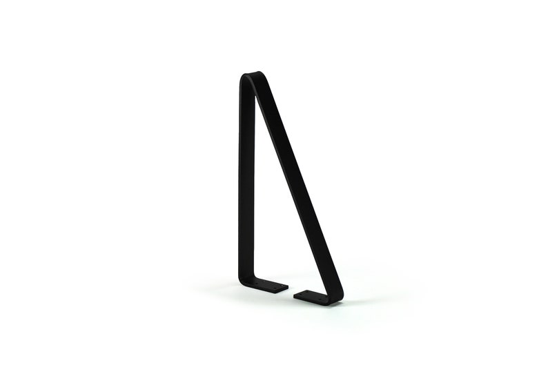 Puede incluir: Un soporte para bicicletas de metal negro con un dise&ntilde;o minimalista. El soporte tiene forma triangular con una parte superior curvada y dos pies planos y rectangulares. Est&aacute; dise&ntilde;ado para sujetar una bicicleta en posici&oacute;n vertical.