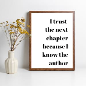 May include: A framed print with a white background and brown frame. The text on the print reads "I trust the next chapter because I know the author."