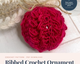 May include: A bright red spherical crochet ornament featuring a textured ribbed pattern and a gold metallic string tied in a bow at the top. The ornament is displayed alongside a cream-colored crocheted item, with text overlay reading Ribbed Crochet Ornament.