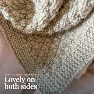May include: A light beige knitted textile featuring a textured pattern with visible loops and stitches. The fabric displays a consistent weave throughout, and the image includes the text: SOFT, SQUISHY, REVERSIBLE Lovely on both sides.