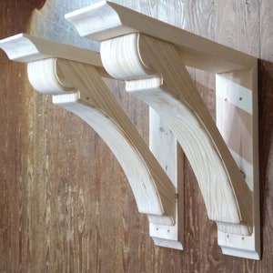 May include: Two unfinished wooden corbels with a curved design. The corbels are mounted to a wall and are ready to be stained or painted.
