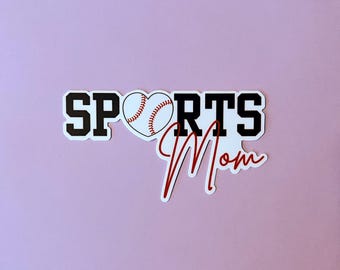 Op de afbeelding: Witte sticker met zwarte tekst die "SPORTS" zegt en een rood hart met een witte honkbal erin. Onder de tekst staat een rood cursief schrift dat "Mom" zegt.