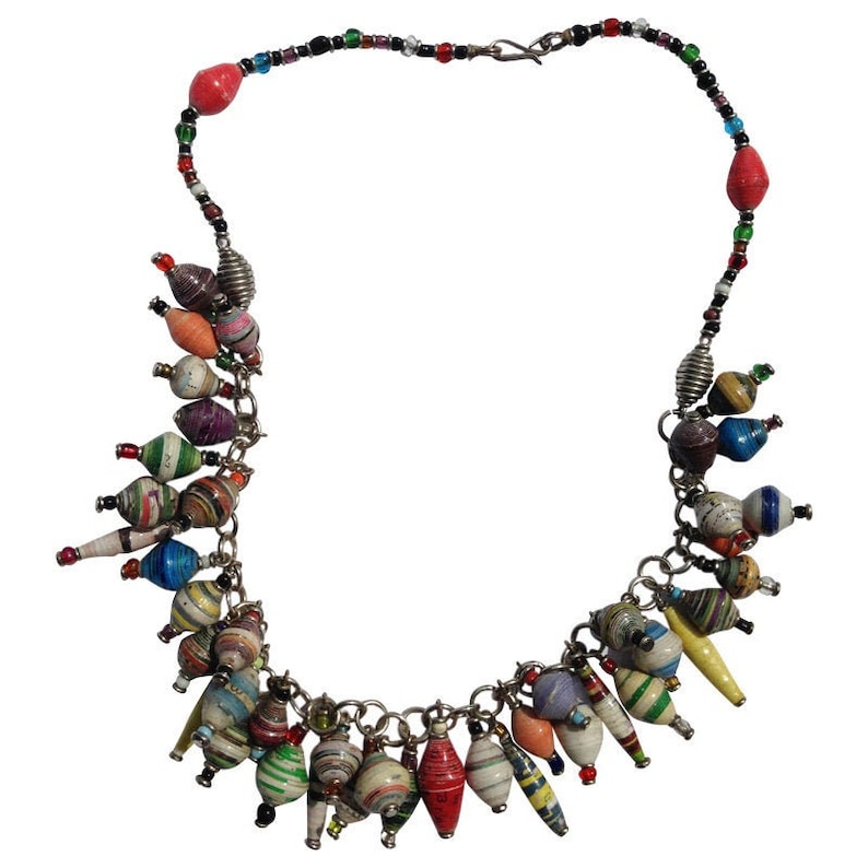 May include: A colorful necklace made of paper beads and silver chain. The beads are in various shapes and sizes, and are strung together in a random pattern. The necklace is a great way to add a touch of bohemian style to any outfit.